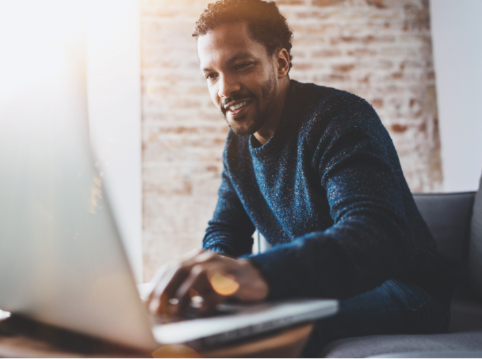 Smiling man types onto a laptop